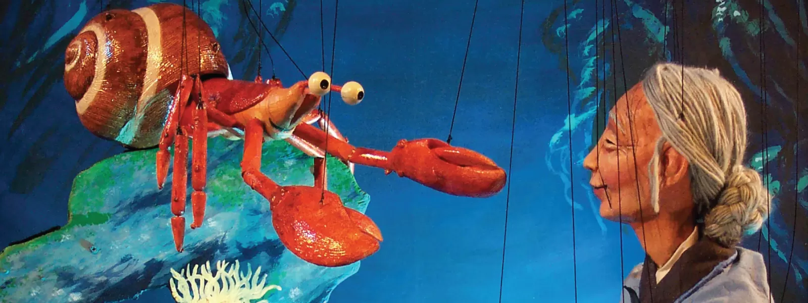 Marionettes of an older woman and a crab in the ocean